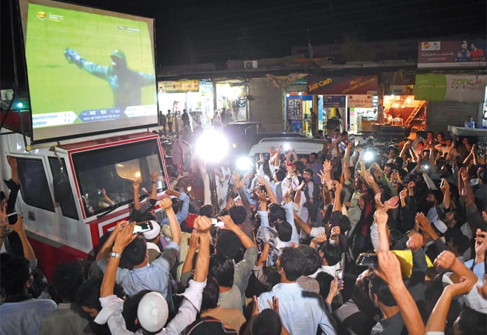 Jubilant youth celebrate Pakistan victory while watching Champions Trophy cricket final on a big screen at Qayyum Stadium Chowk, Peshawar, on Sunday. — Photo by Shahbaz Butt