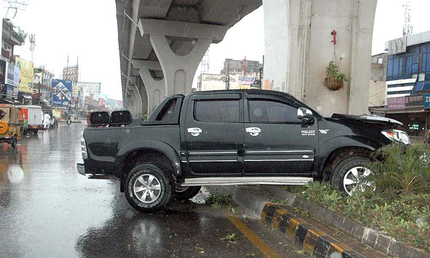 بارش کے دوران راولپنڈی کی ایک سڑک پر گاڑی فٹ پاتھ پر چڑھ گئی — فوٹو/ اے پی پی