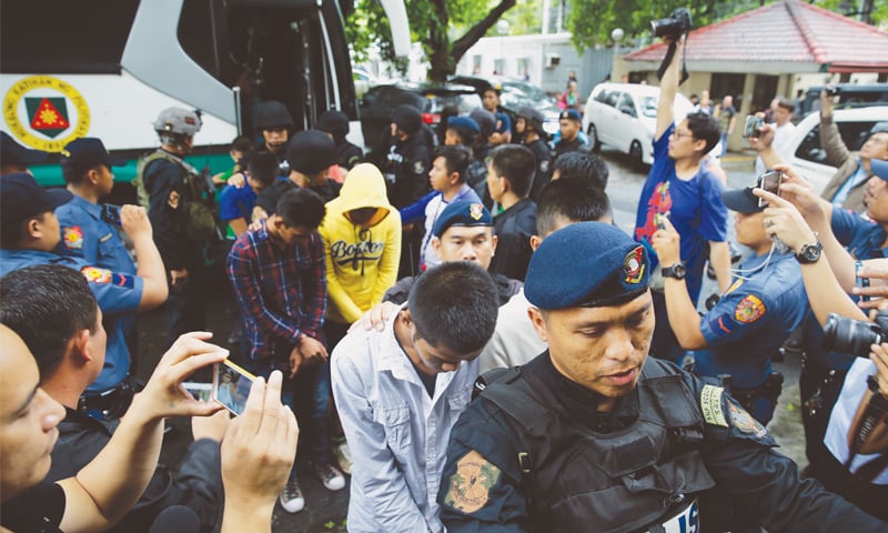 Manila: Police escort men suspected to be en route to reinforce the Marawi militants as they arrive at the Department of Justice on Friday.&mdash;AP