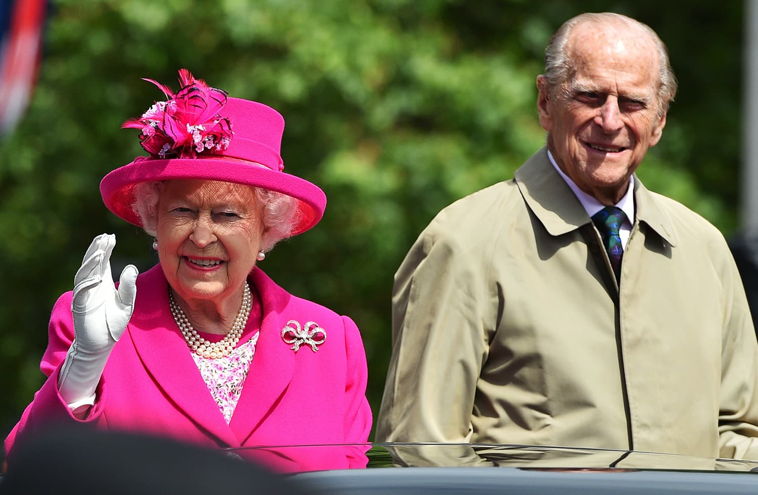 Queen Elizabeth II and Prince Philip wave to guests from their car as they attend the Patron's Lunch on the Mall, an event to mark her official 90th birthday in London. — AFP