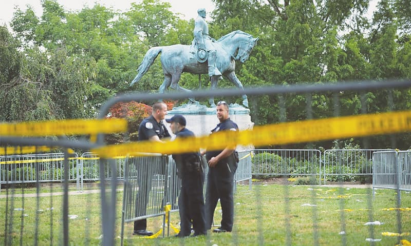 POLICEMEN guard the statue of Gen Robert E. Lee, which is at the centre of the controversy.—AFP