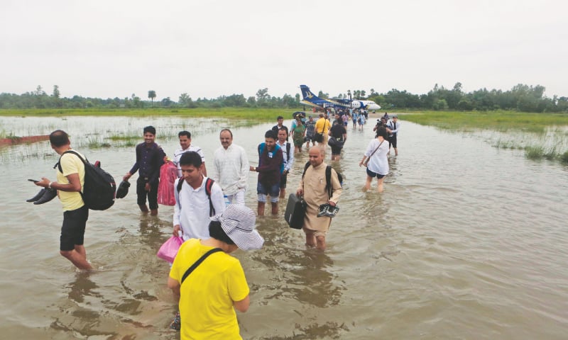 Passengers walk through the flooded Janakpur airport in Nepal on Sunday.&mdash;AP