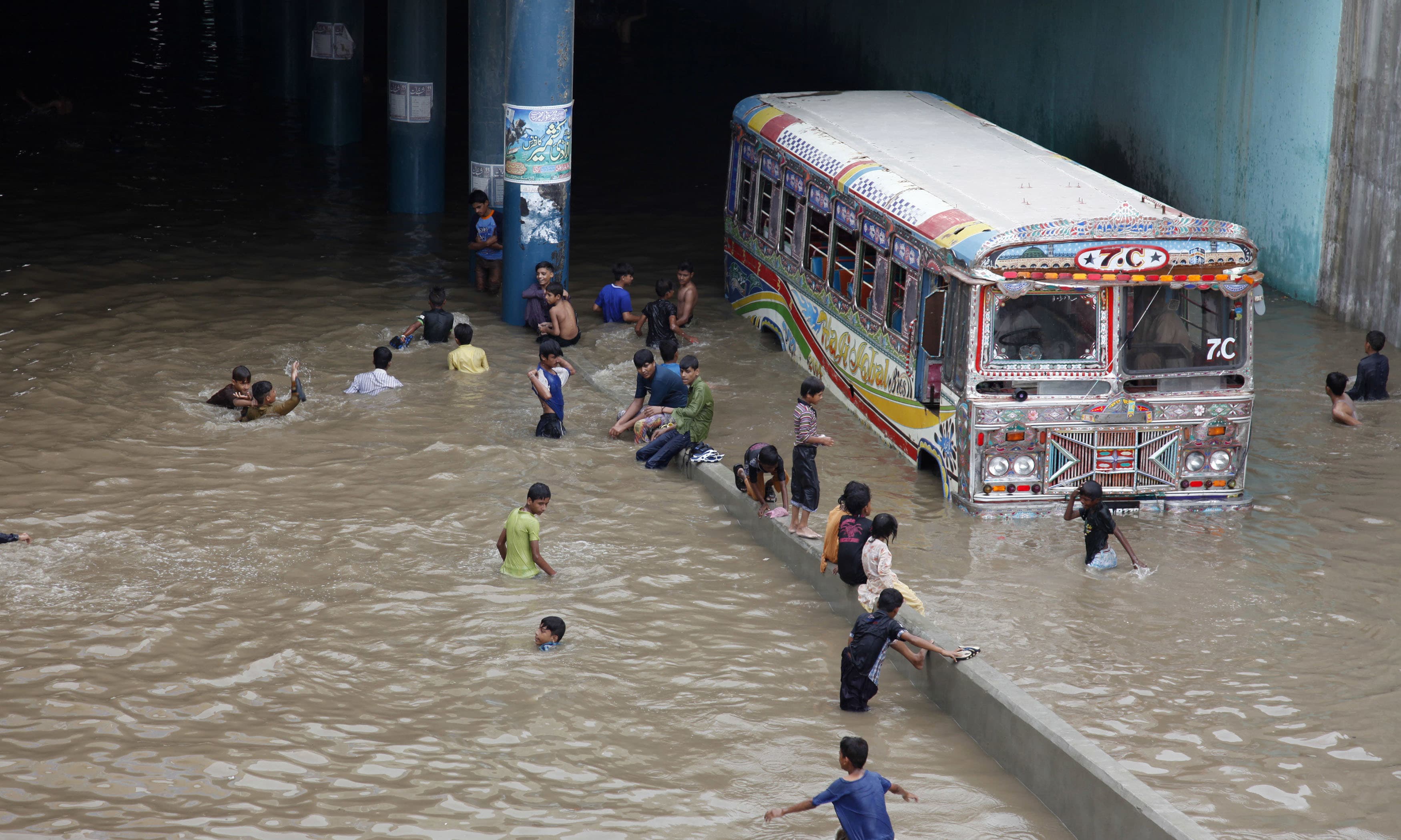 Children play in an underpass filled with rainwater in Karachi. ─ AP