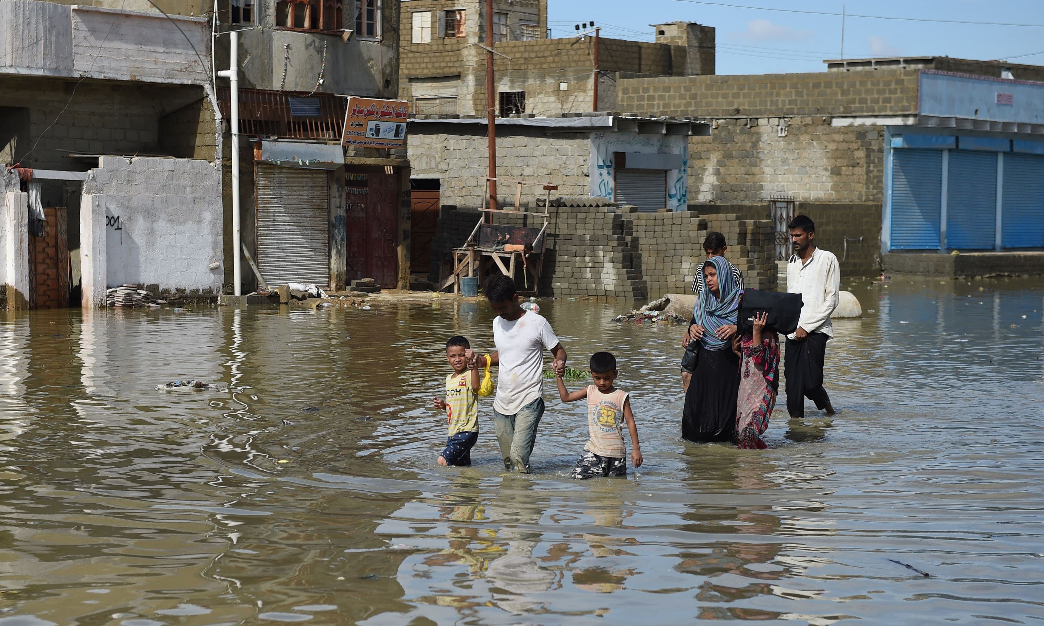 A family makes their way on a flooded street after heavy rain in Karachi on August 31, 2017. ─ AFP