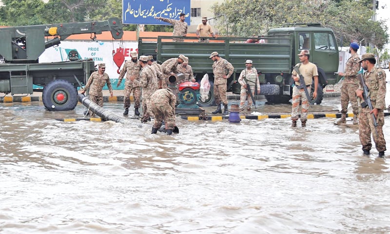 ACROSS the city, scenes of devastation were widespread in the wake of the rains on Thursday. Pak Army jawans help drain rainwater at Ayesha Manzil.—Agencies