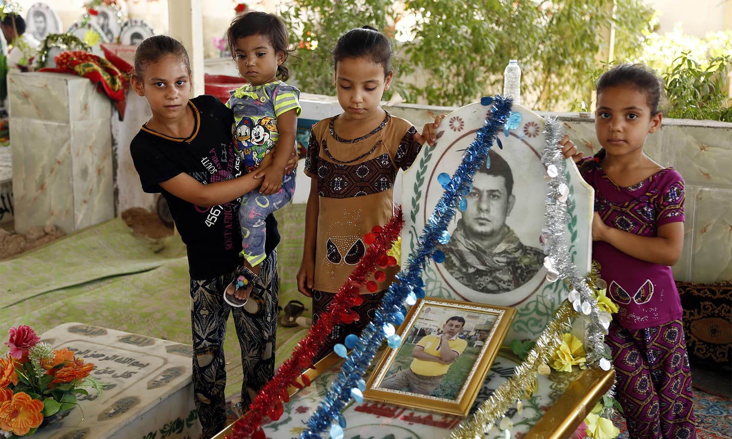 Iraqis pose for a photo as they visit grave of a relative killed in the combat against the militant Islamic State group at the Wadi al-Salam cemetery in Najaf on the first day of the Eidul Azha.—AFP