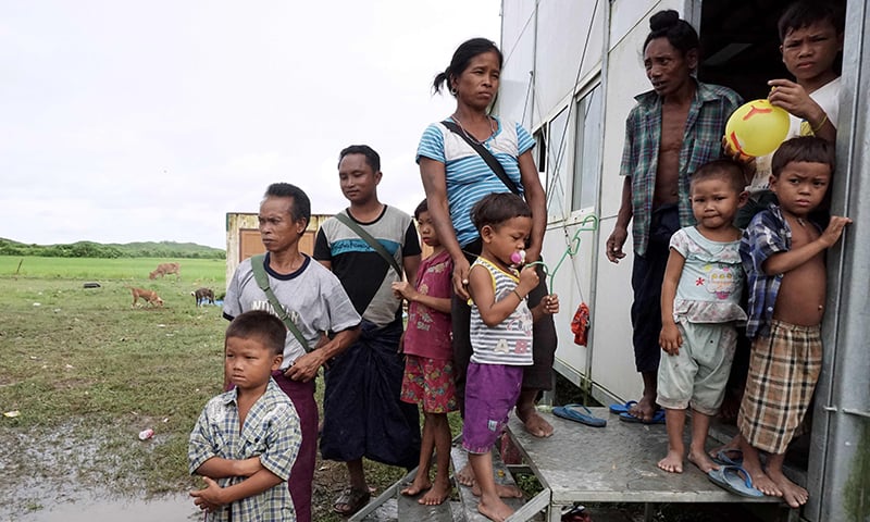 Ethnic Mro families who fled their village because of unrest stand in the entrance of a temporary shelter in a village near Maungdaw town in northern Rakhine State.─AFP