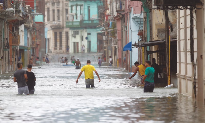 People wade through a flooded street (top) and return home amid uprooted utility poles (bottom right) after the passage of Hurricane Irma in Havana on Sunday.—Agencies People wade through a flooded street (top) and return home amid uprooted utility poles (bottom right) after the passage of Hurricane Irma in Havana on Sunday.—Agencies