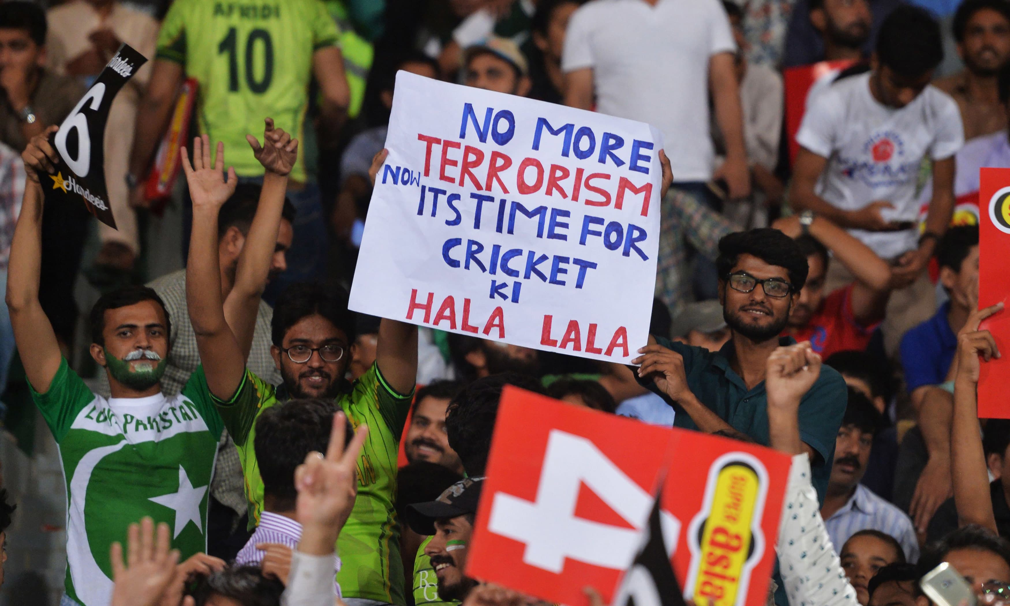 Spectators hold placards during the second T20 International match between the World XI and Pakistan. — AFP