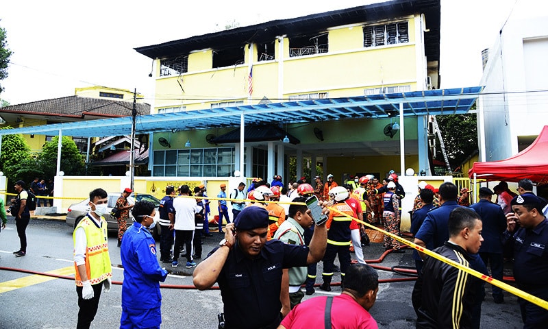 Police and rescue personnel work at an Islamic religious school cordoned off after the fire on the outskirts of Kuala Lumpur .—AP