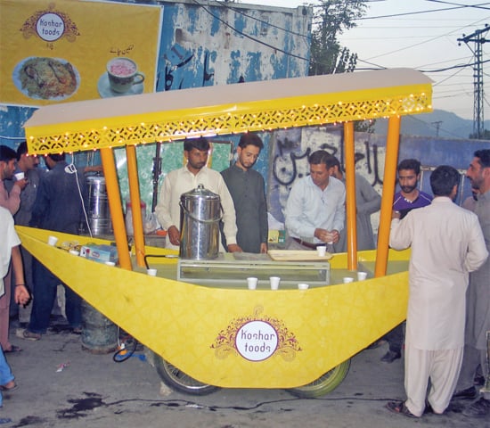 A customer buys food from a mini eatery on a replica of a shikara in Muzaffarabad. &mdash; Photo by the Writer