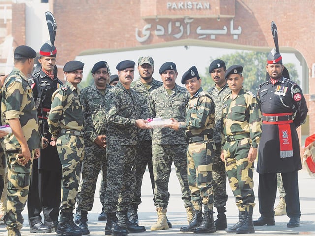 INDIAN Border Security Force Commandant Sudeep (fourth-right) presents sweets to Wing Commander Bilal (fifth-left) on the occasion of Diwali at the Wagah border post on Thursday. The festival of lights was celebrated on Oct 19.—AFP