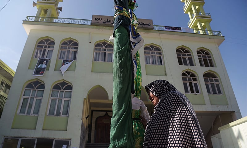 An elderly Afghan resident holds a religious flag outside the Imam Zaman mosque after a suicide attack during Friday evening prayers in Kabul. ─ AFP