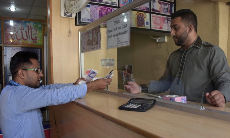 This Oct 19 photograph shows a visiting dual Pakistani Kashmiri and British citizenship holder (left) exchanging British pounds at a remittance shop in Mirpur.&mdash;AFP