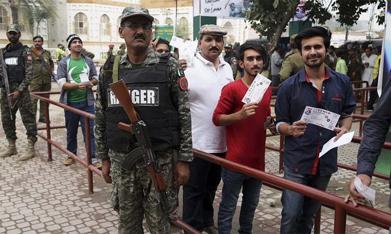 Soldiers stand guard next to cricket fans arriving to watch the third T20 match. ─AP