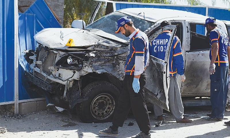 VOLUNTEERS examine the vehicle of the police officer at the site of the suicide attack on Thursday.—AFP