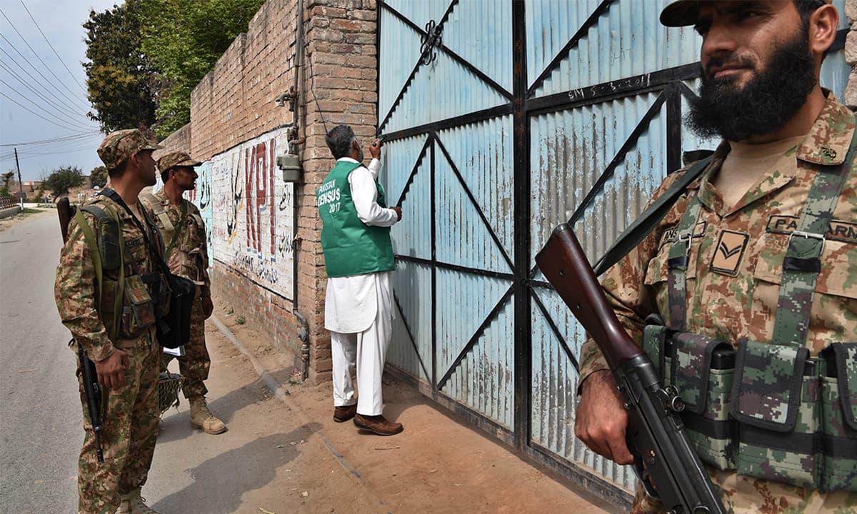 An enumerator, escorted by security personnel, marks a house during the census in Khyber Pakhtunkhwa | Abdul Majeed Goraya, White Star