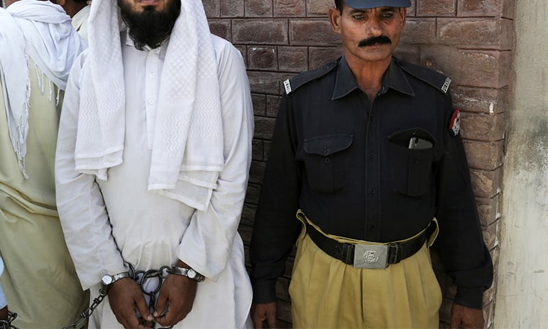 The handcuffed cleric who allegedly raped a child stands outside a court in Kehror Pakka. ─ AP