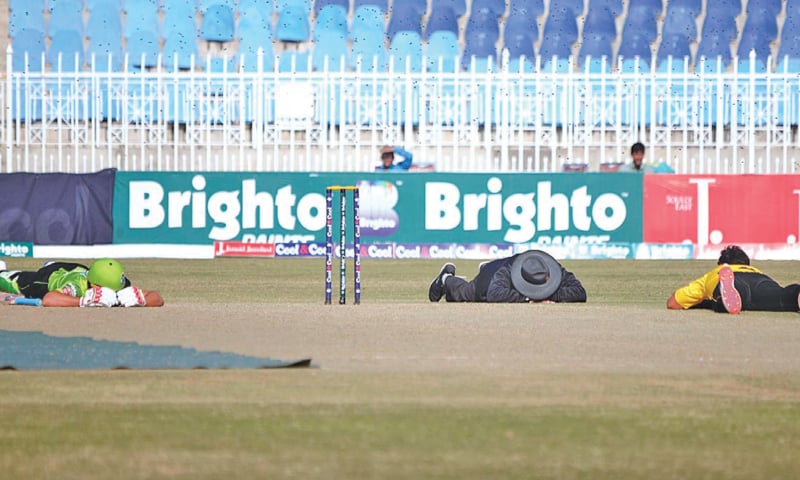 RAWALPINDI: (L to R) Lahore Whites&rsquo; captain Salman Butt, umpire Aaley Haider and Peshawar batsman Sohail Khan lie on the pitch to evade an attack of bees during the National T20 Cup match at the Pindi Cricket Stadium on Tuesday.&mdash;APP