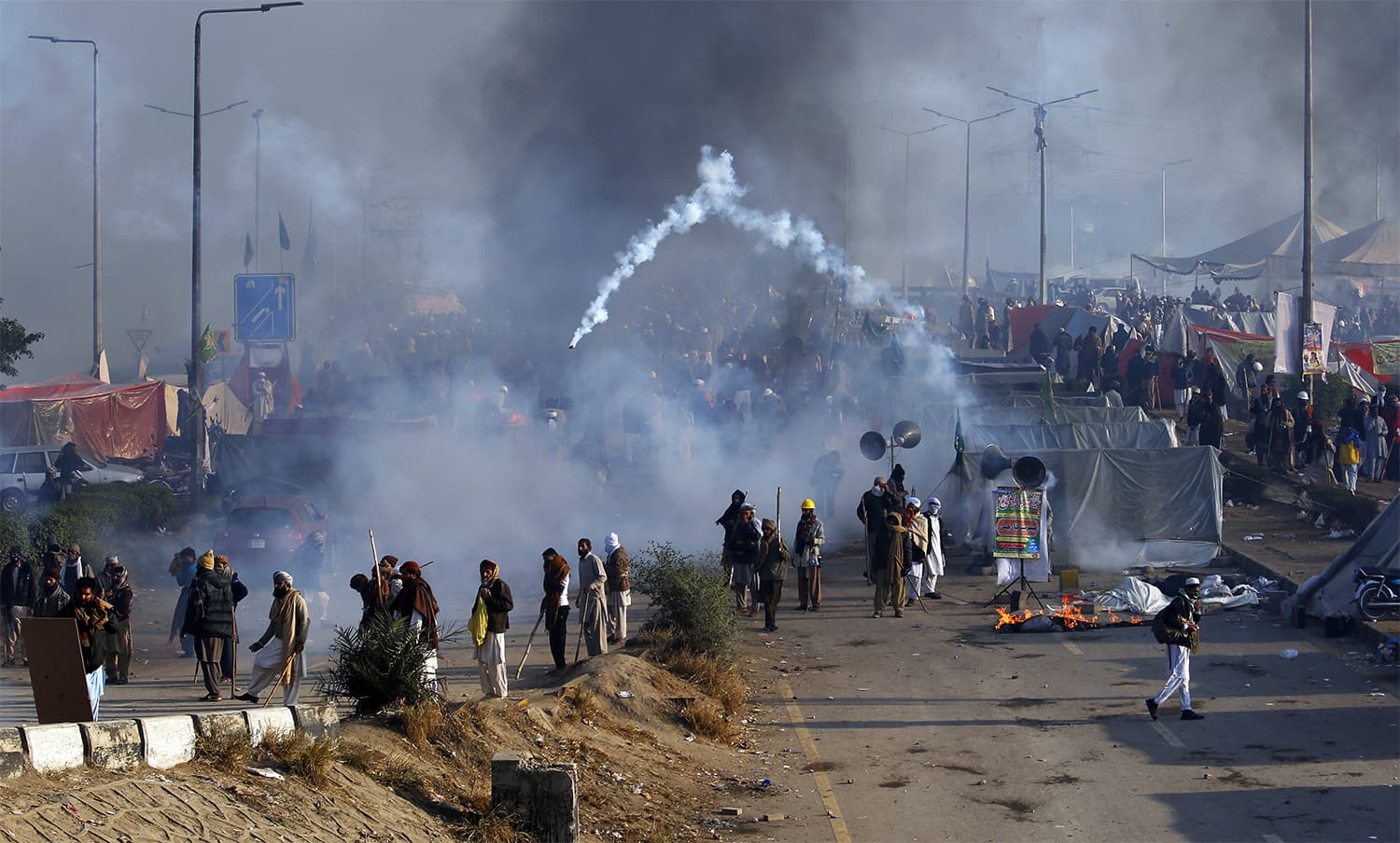 Protesters hurl back a tear gas shell fired by police during a clash. ─ AP