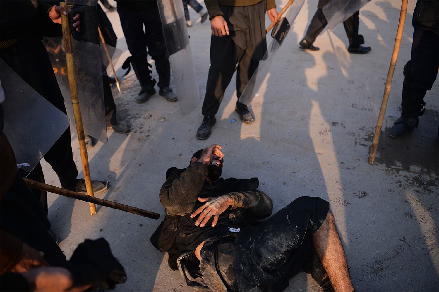 Riot policemen gather around an injured TLY protester in Islamabad. ─ AFP