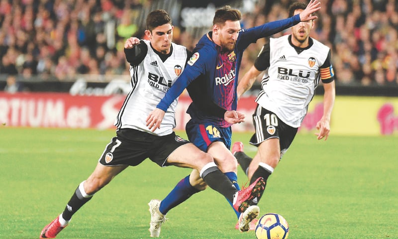 VALENCIA: Manuel Guedes (L) of Valencia vies for the ball with Barcelona&rsquo;s Lionel Messi during their La Liga match at the Mestalla.&mdash;AFP