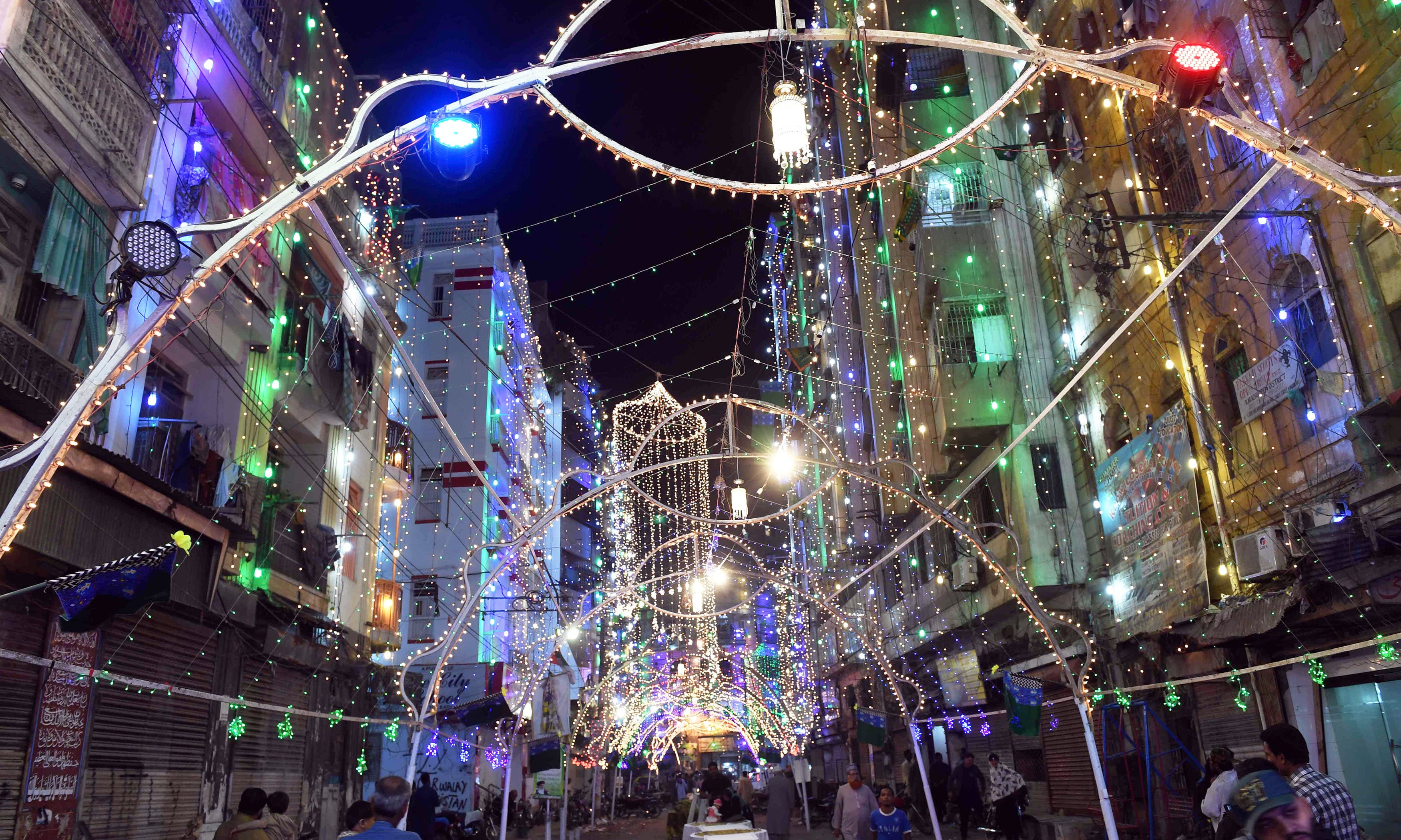 People walk through a street decorated with lights in Karachi. &mdash;AFP