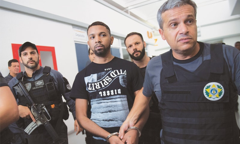 RIO DE JANEIRO: Rogerio Avelino da Silva (centre), is being escorted by police.—AFP RIO DE JANEIRO: Rogerio Avelino da Silva (centre), is being escorted by police.—AFP