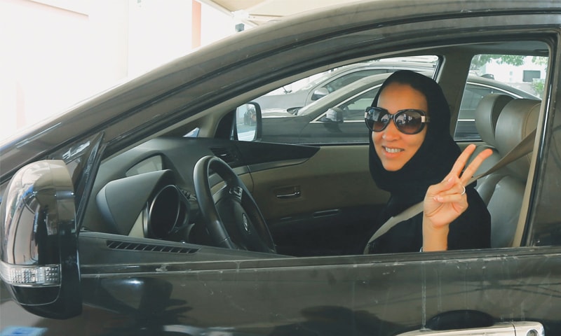 Manal al-Sharif flashes the victory sign from behind the wheel of her car | AFP