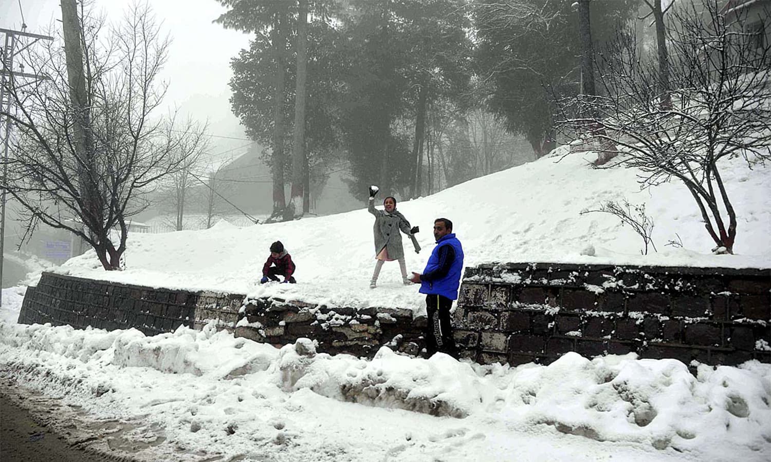 Children play with snow during the first snowfall of the year in the hill resort of Murree.— APP