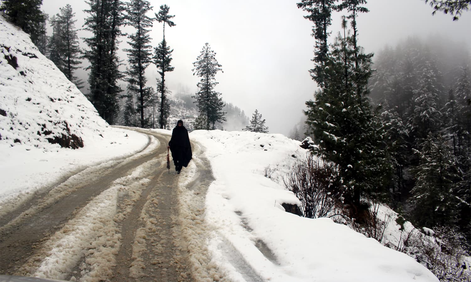 A man walks on a road covered with snow in Shangla.— Umar Bacha