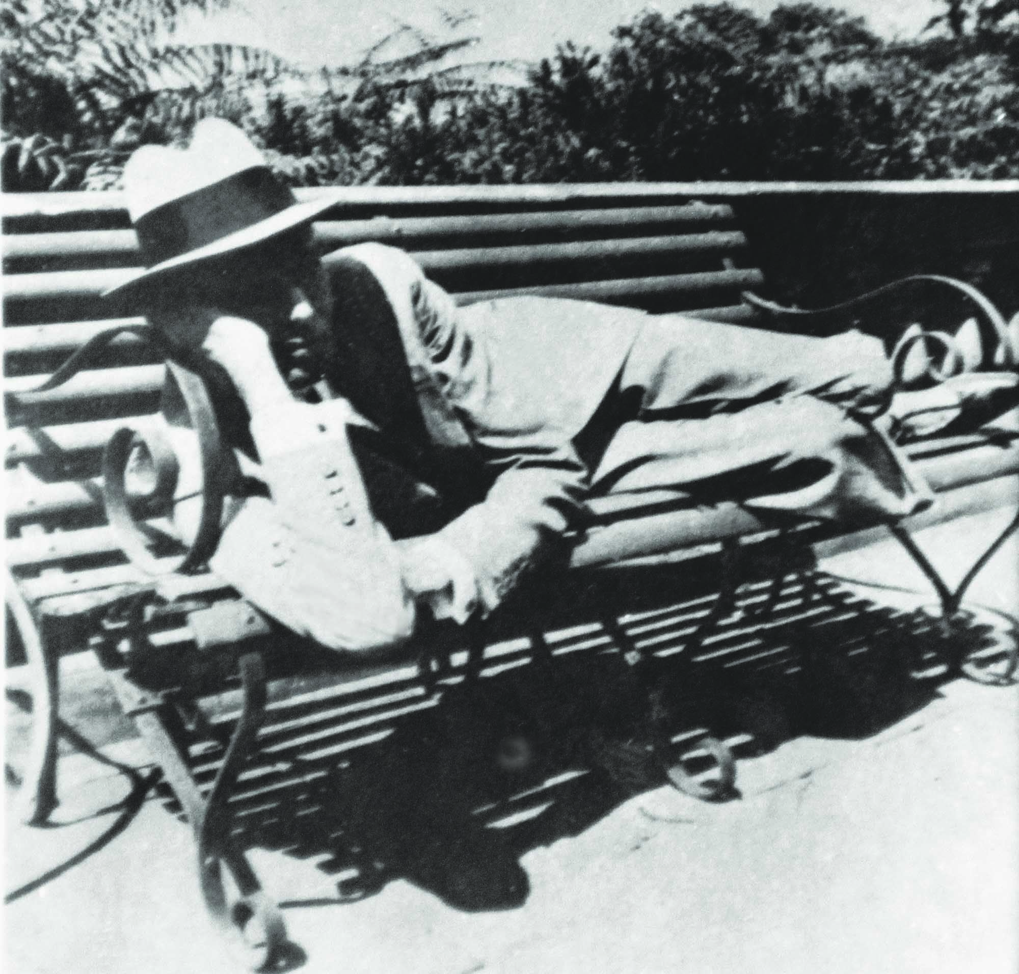 Elegantly dressed in a suit and wearing a hat, Quaid-i-Azam Mohammad Ali Jinnah is seen relaxing on a bench during a visit to Simla. | Photo: PID