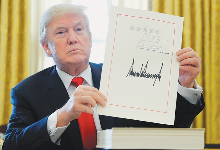 WASHINGTON: US President Donald Trump displays his signature after signing the $1.5 trillion tax overhaul plan in the Oval Office of the White House on Dec 22.&mdash;Reuters