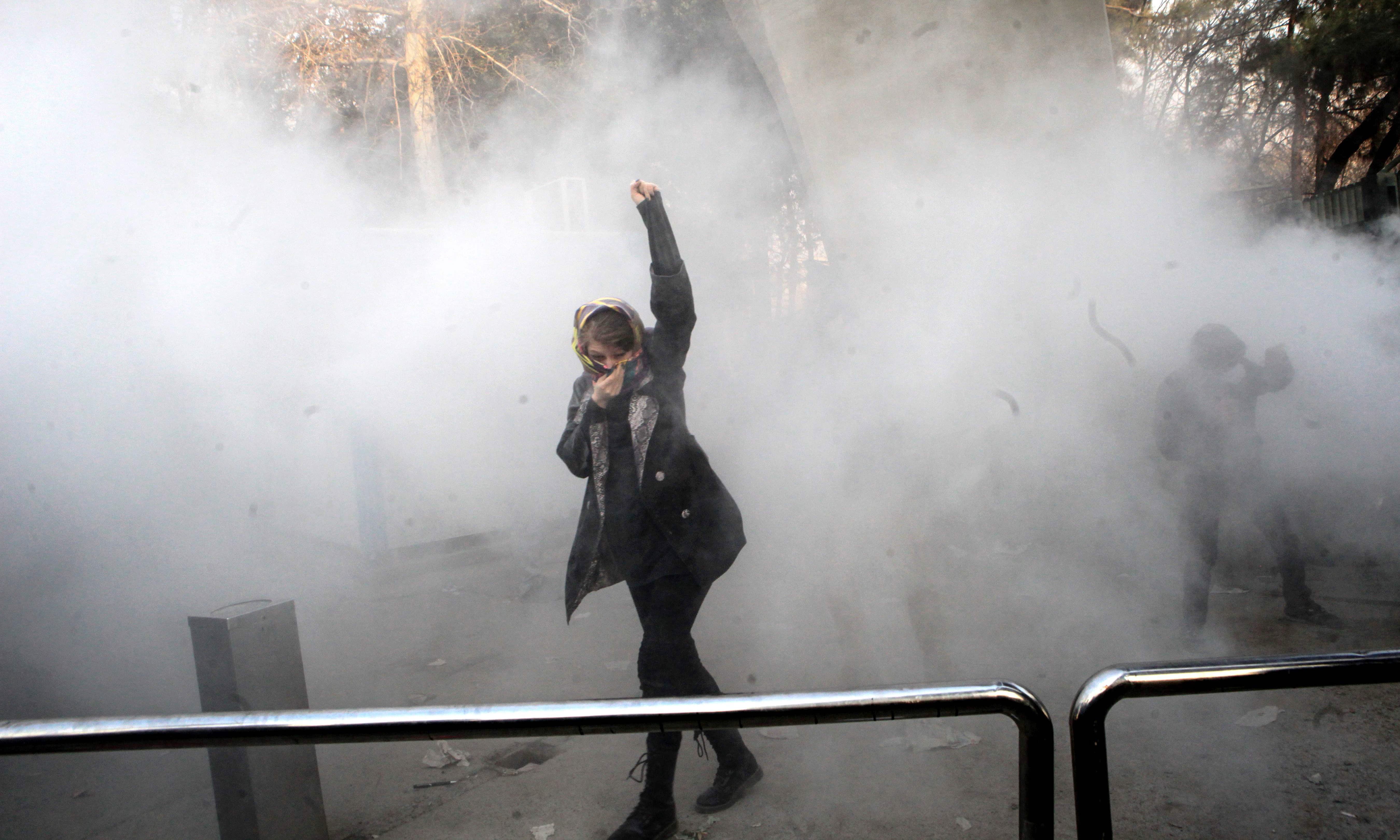 An Iranian woman raises her fist amid the smoke of tear gas at the University of Tehran during a protest driven by anger over economic problems, in the capital Tehran on December 30, 2017. —AFP