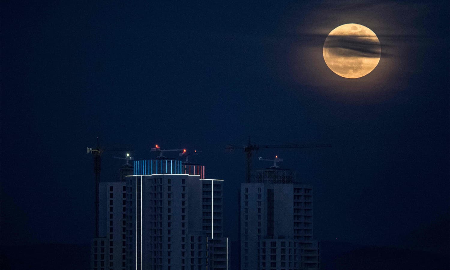 The moon rises next to the city's highest buildings in Skopje.— AFP