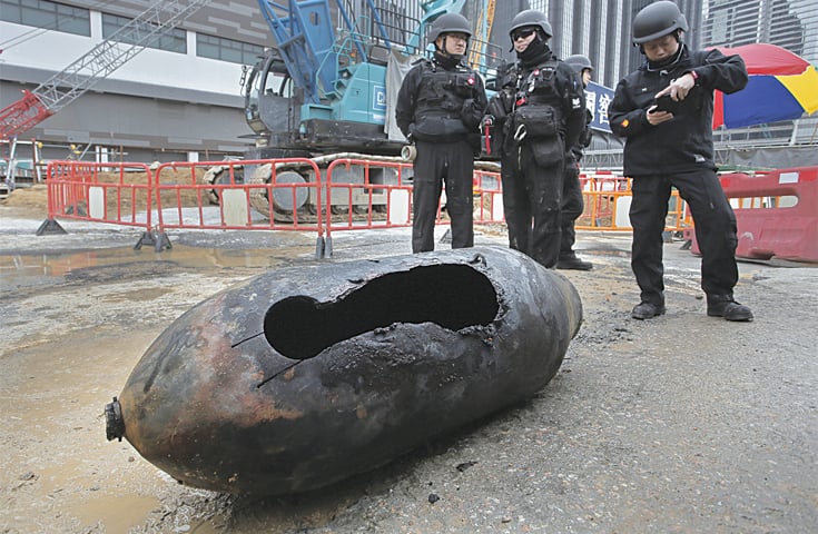 Hong Kong: Explosive ordnance disposal experts look at the deactivated bomb.&mdash;AP
