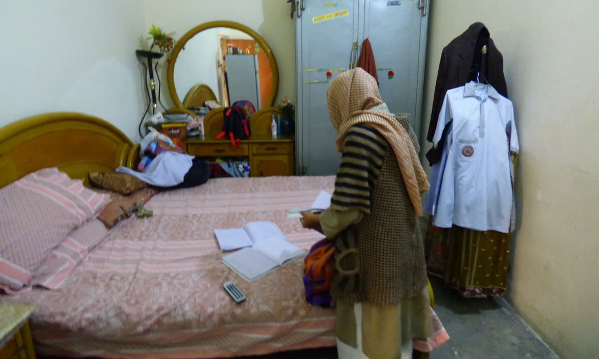 Zainab’s mother, Nusrat Bibi, looks through her daughter’s books in their home | Tariq Mahmood, White Star