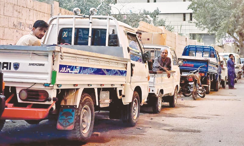 Loading pickup trucks for hire with workers parked by the roadside.