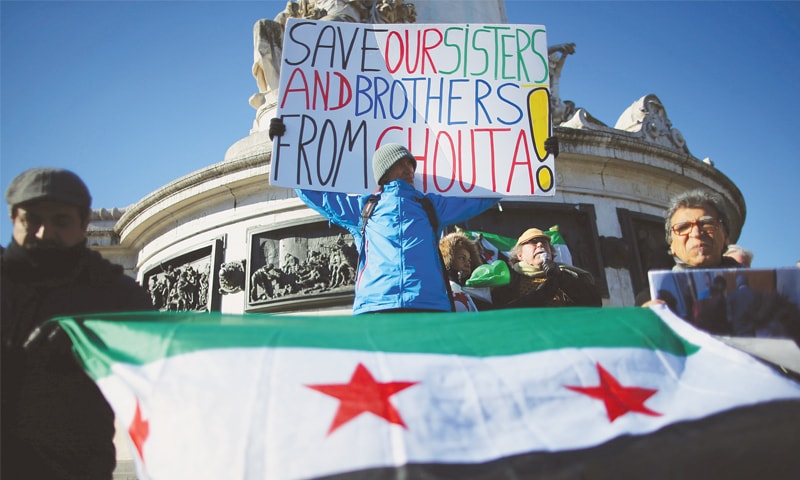 PARIS: Protesters hold a placard during a demonstration on Sunday to express solidarity with the people of Syria.—Reuters