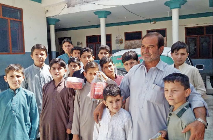 Yousaf Hussain Lala with the children at his orphanage in Parachinar. — Dawn