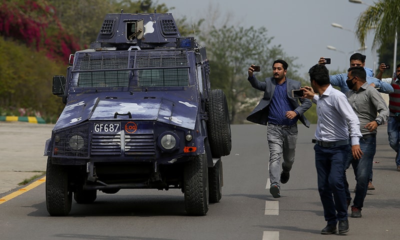 Journalists chase an armoured vehicle carrying Rao Anwar. — AP