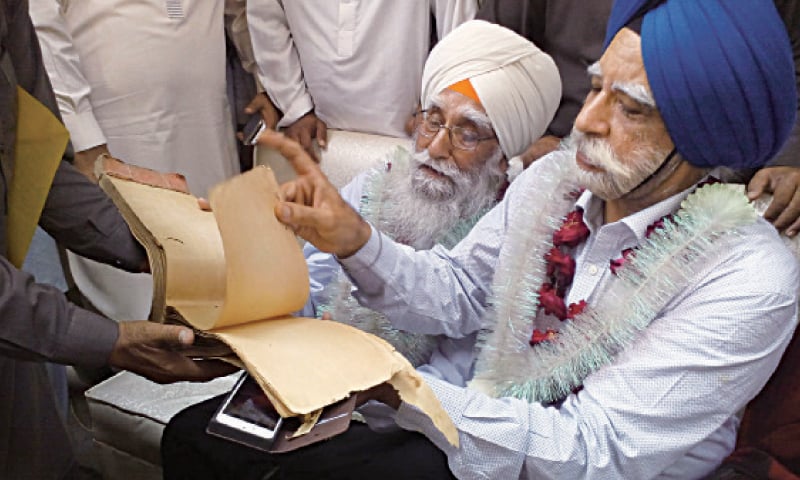Sardar Harbhajan Singh Bhatia has a glance at a leaf of the ledger. &mdash; Dawn