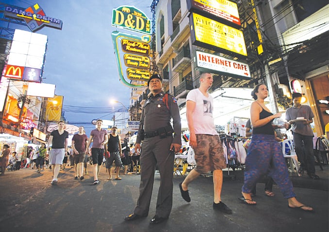 A THAI policeman stands guard as tourists walk along Khao San road in Bangkok.—Reuters
