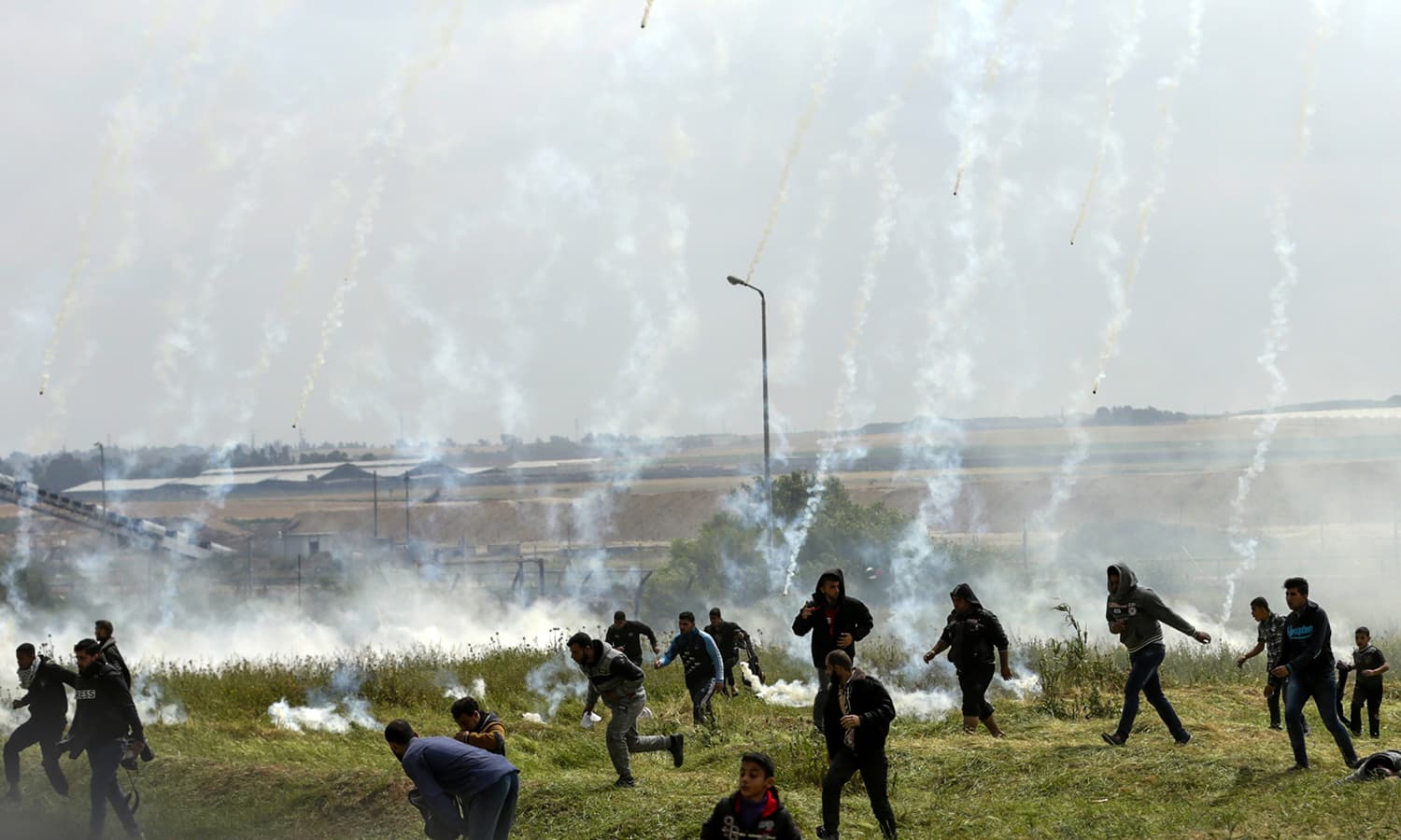 Palestinians fleeing as tear gas grenades begin to drop during a demonstration near the border with Israel east of Gaza City. ─AFP