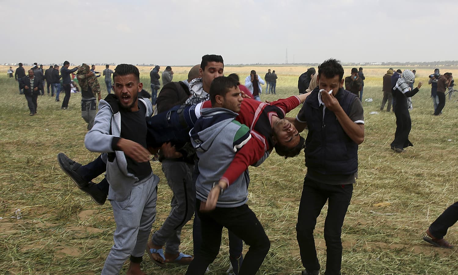 Palestinian protesters evacuate a wounded youth during clashes with Israeli troops along the Gaza Strip border. ─AP