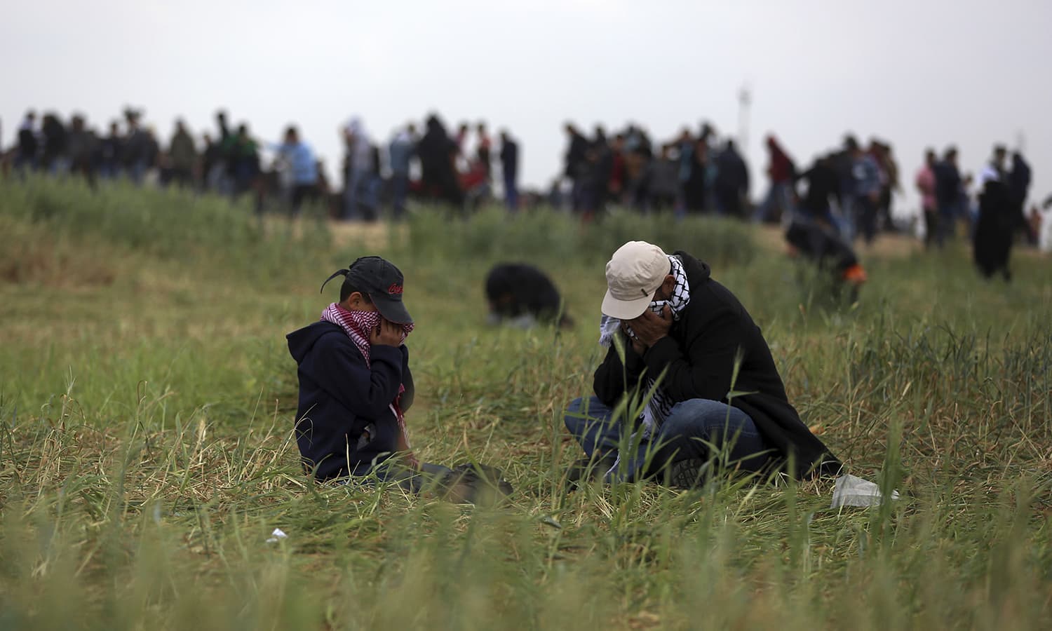 A Palestinian man and his son cover their faces from tear gas fired by Israeli troops during a demonstration near the Gaza Strip border with Israel. ─AP