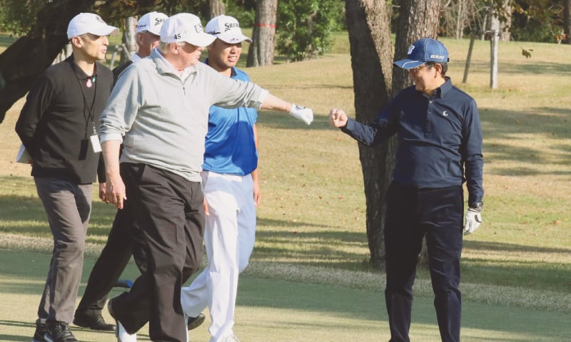 US President Donald Trump (centre) fist-bumps Japanese Prime Minister Shinzo Abe (right) while playing golf at the Kasumigaseki Country Club Golf Course in Kawagoe, Saitama prefecture, outside Tokyo, in this file picture taken on Nov 5, 2017.&mdash;AFP