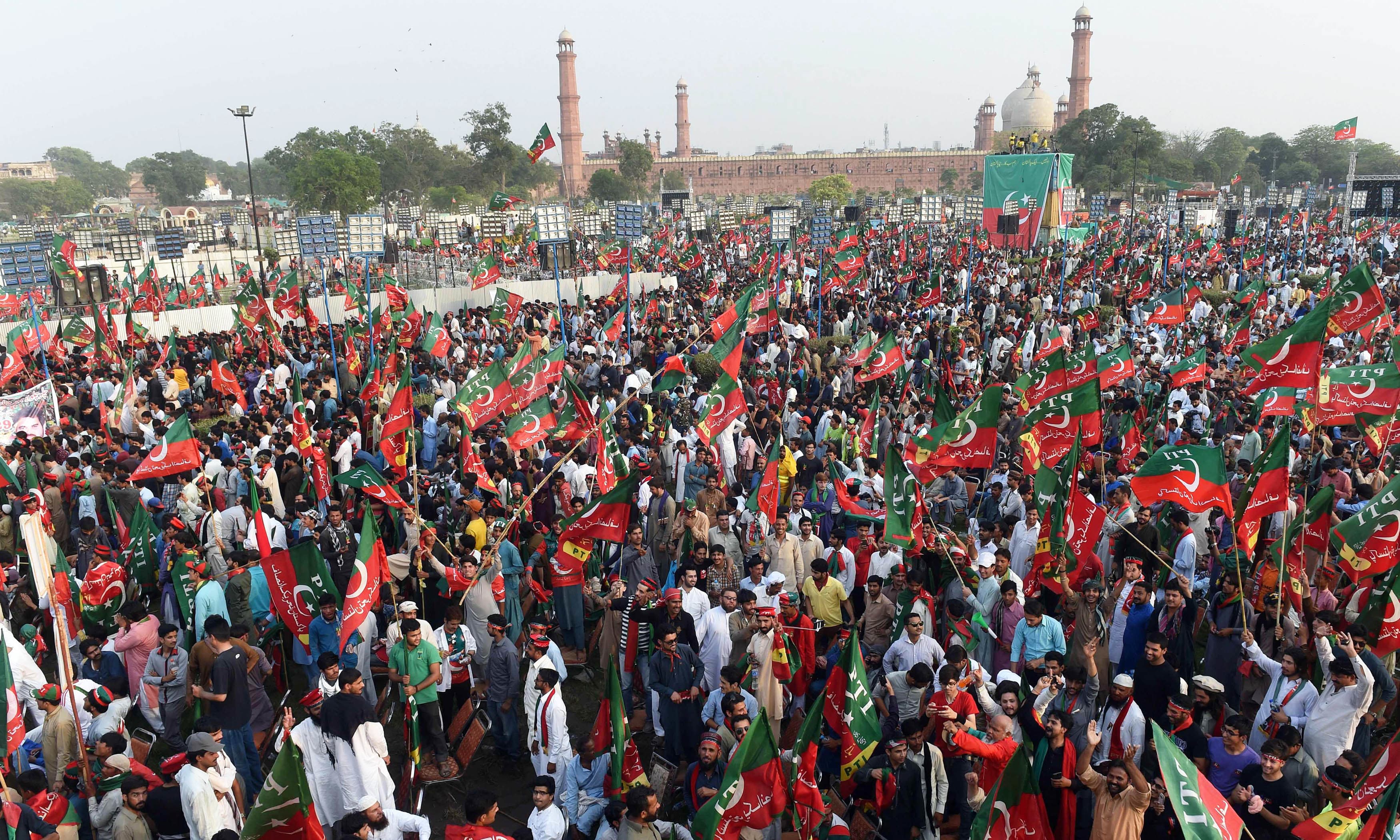 Supporters gesture and wave PTI flags as they attend a rally in Lahore. —AFP