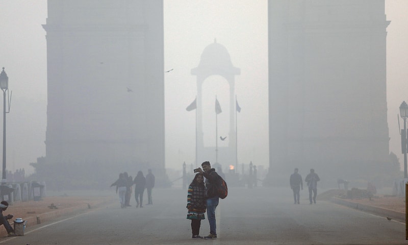 Two youngsters take a selfie in front of the India Gate on a smoggy morning in New Delhi.—Reuters