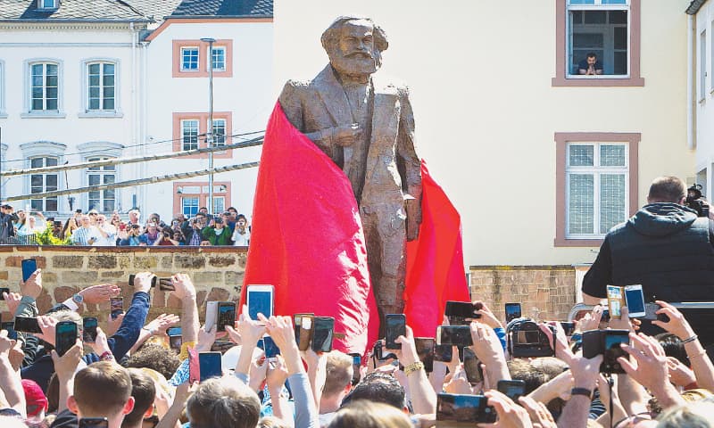 TRIER: Frederique Longuet Marx (top left), great-great-granddaughter of Karl Marx, gives a speech prior to the opening of an exhibition at the birth house of Karl Marx on Saturday. Chinese artist Wu Weishan (top right) poses next to his bronze statue of Marx, presented by China, to mark the 200th birth anniversary of the German philosopher. People attending the event take photos of the statue as it is unwrapped and shows Marx in a frock coat striding forward.&mdash;Agencies